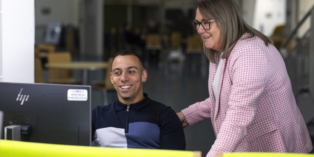A staff member and their employee working collaboratively with AI on a computer.